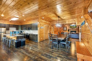 A wooden interior with a kitchen, dining area, and a fireplace. - Splash Mansion - Indoor Pool and Theater (Sevierville)