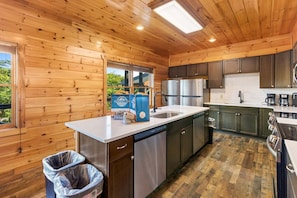 A modern kitchen with wooden walls, stainless steel appliances, and a large window. - Splash Mansion - Indoor Pool and Theater (Sevierville)