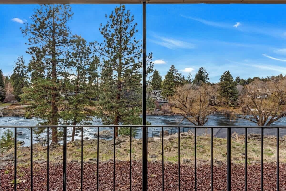Une rivière bordée d’arbres, avec une maison en arrière-plan.