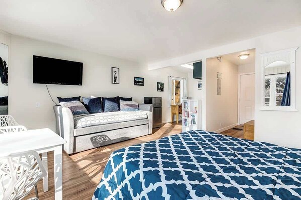 A bedroom with a bed, a TV, a desk, and a bookshelf.