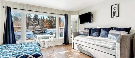 Une chambre à coucher avec un lit, un canapé, une télévision et une fenêtre avec des rideaux.