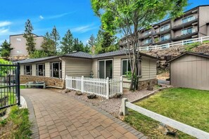 Un immeuble résidentiel avec une allée pavée, une clôture blanche en bois et un petit jardin.