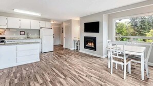 A modern kitchen with white cabinets, a built-in island, and a fireplace.
