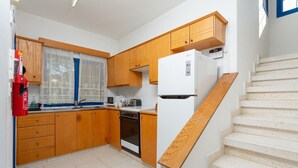 A compact kitchen with wooden cabinets, a white refrigerator, a microwave, and a stove. - Villa Charoula Tria Large Private Pool, A/C, WiFi (Polis)