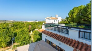 A white building with a red-tiled roof, a balcony with a black railing, and a view of a green landscape. - Villa Charoula Tria Large Private Pool, A/C, WiFi (Polis)
