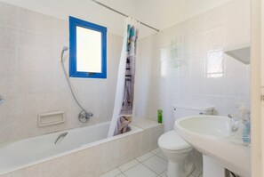 Een badkamer met een bad, toilet en wastafel.