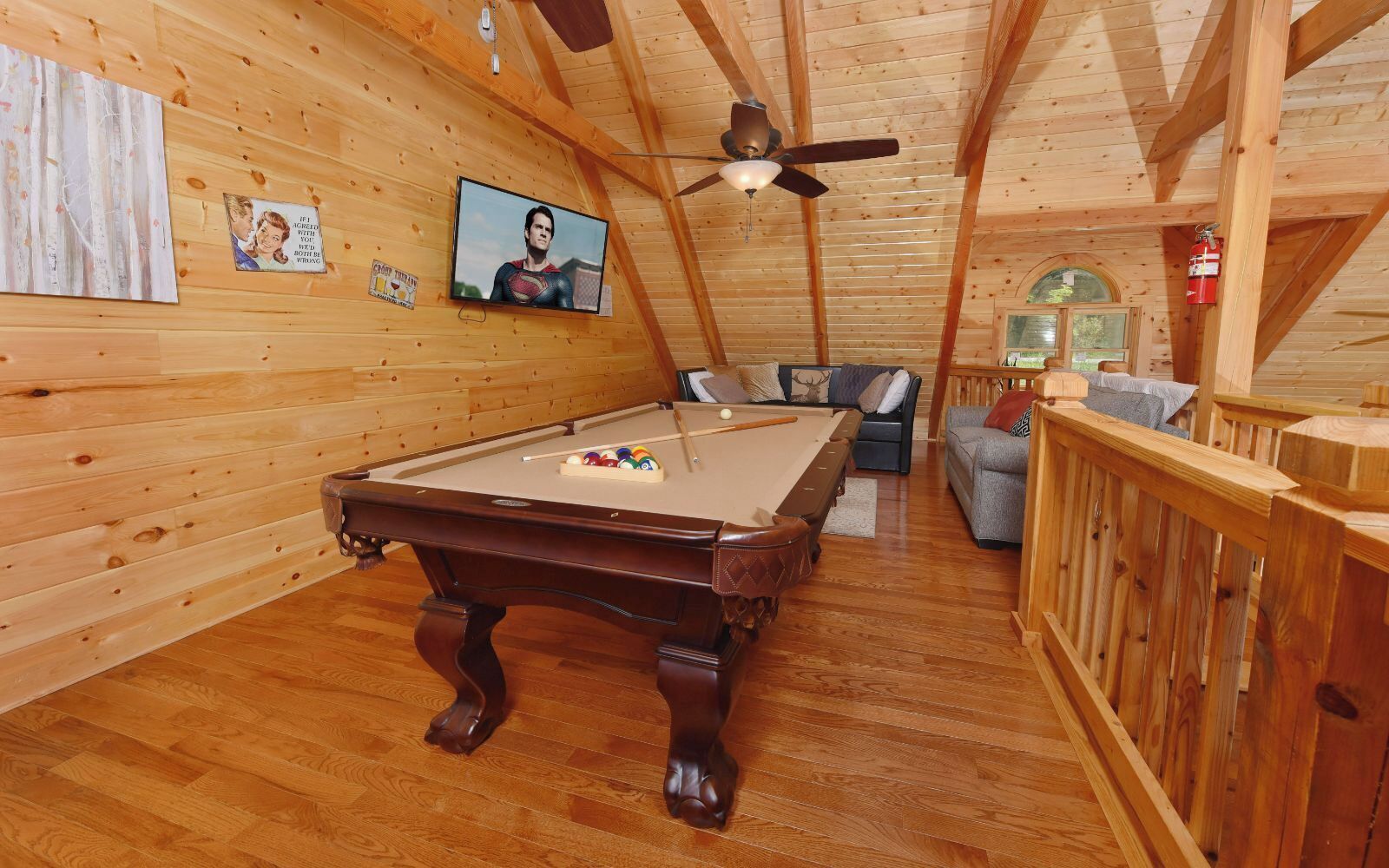 Ein Holzinterieur mit Poolbillard, Deckenventilator und Fernseher.