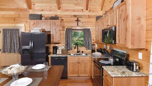 A compact kitchen with wooden cabinets, a refrigerator, a microwave, and a stove.