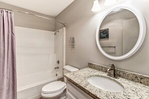 Bathroom features a walk-in shower with a glass door, a toilet, and a granite sink.