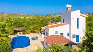 A modern villa with a swimming pool, a covered patio, and a view of the sea. - Villa Charoula Pente (Polis)