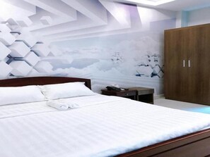 A bedroom with a bed, a wooden wardrobe, and a wall with a geometric pattern.