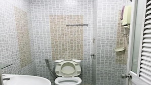 Une salle de bain comprenant des toilettes, un lavabo et un espace douche.