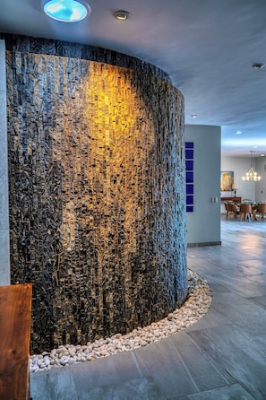 Een modern interieur met een structuurwand, een eethoek en een kroonluchter.