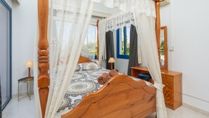 Un letto a baldacchino con tenda, un comodino, uno specchio e vista sull'esterno.