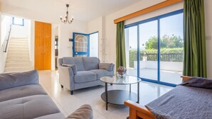 Un soggiorno moderno con un divano grigio, un tavolino da caffè rotondo in vetro e una porta con cornice blu.