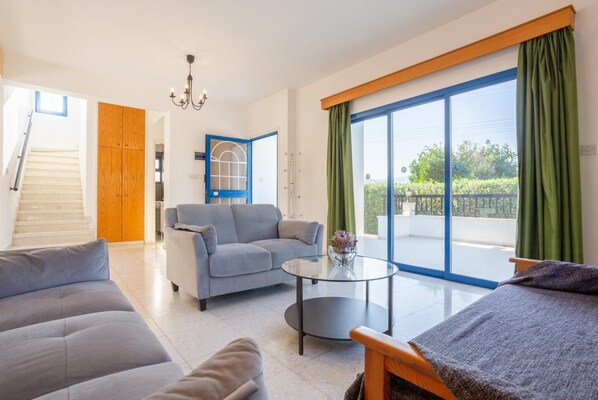 Ein modernes Wohnzimmer mit einem grauen Sofa, einem runden Glastisch und einer türartig blauen Umrandung.