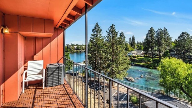 Ein Balkon mit Blick auf einen Fluss, Bäume und Häuser.