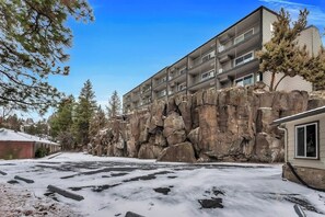 Un immeuble à plusieurs étages doté de balcons, situé à côté d’une falaise rocheuse.