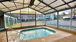 A covered outdoor swimming pool with a metal roof, a bench, and a view of a parking lot. - Cozy one-bedroom condo overlooking the Deschutes (Bend)