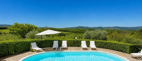 A swimming pool with lounge chairs and a view of the countryside.