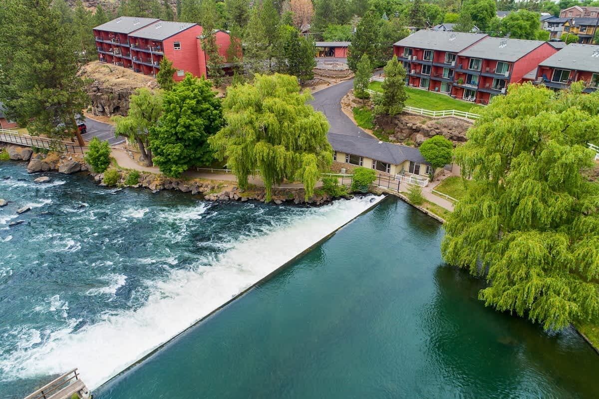 A river flowing through a residential area with red buildings and lush greenery.