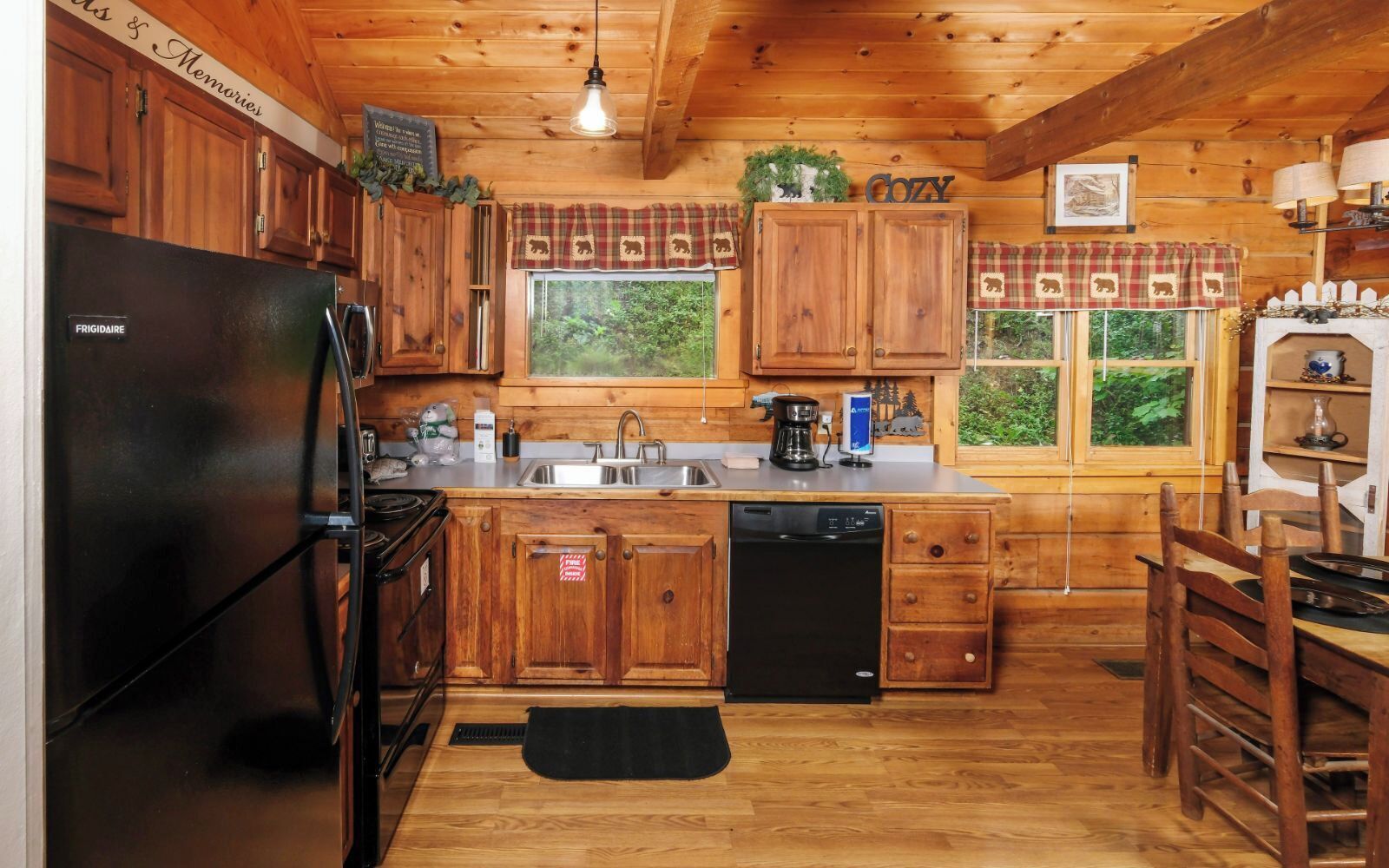 A cozy cabin-style kitchen with wooden cabinets, a black refrigerator, a coffee maker, and a dishwasher.