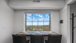 Un comedor con una mesa dispuesta para cuatro, una ventana con persianas y vistas al paisaje.