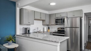 Una cocina moderna con armarios grises, electrodomésticos de acero inoxidable y encimera de granito.