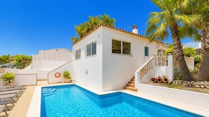 Un edificio blanco con piscina, escaleras y palmeras.