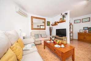 Een woonkamer met een bank, salontafel, televisie en een eettafel gedekt met borden en glazen.