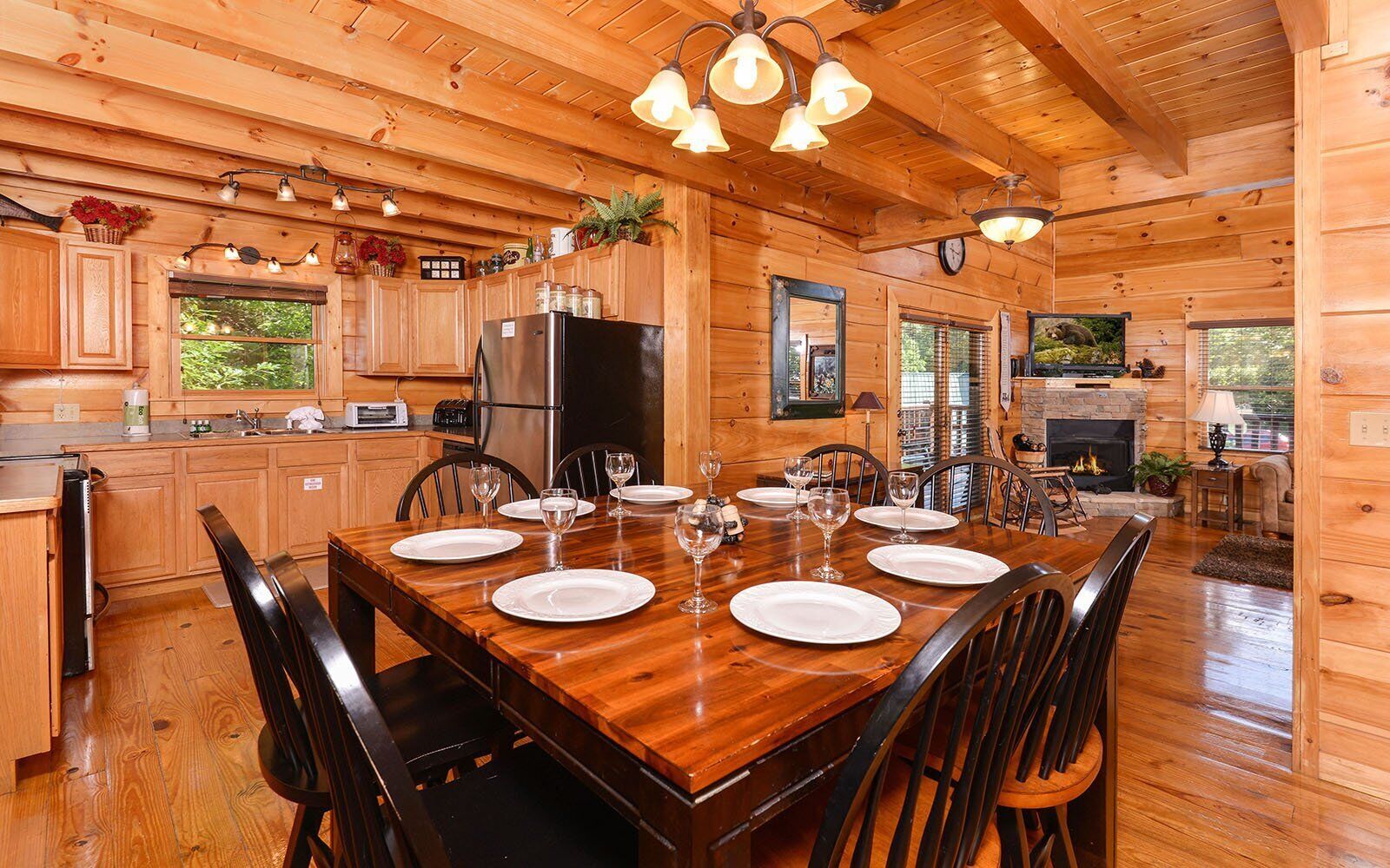 L’intérieur d’un chalet en bois comprend une salle à manger avec une table dressée pour six personnes, un coin cuisine et une cheminée.