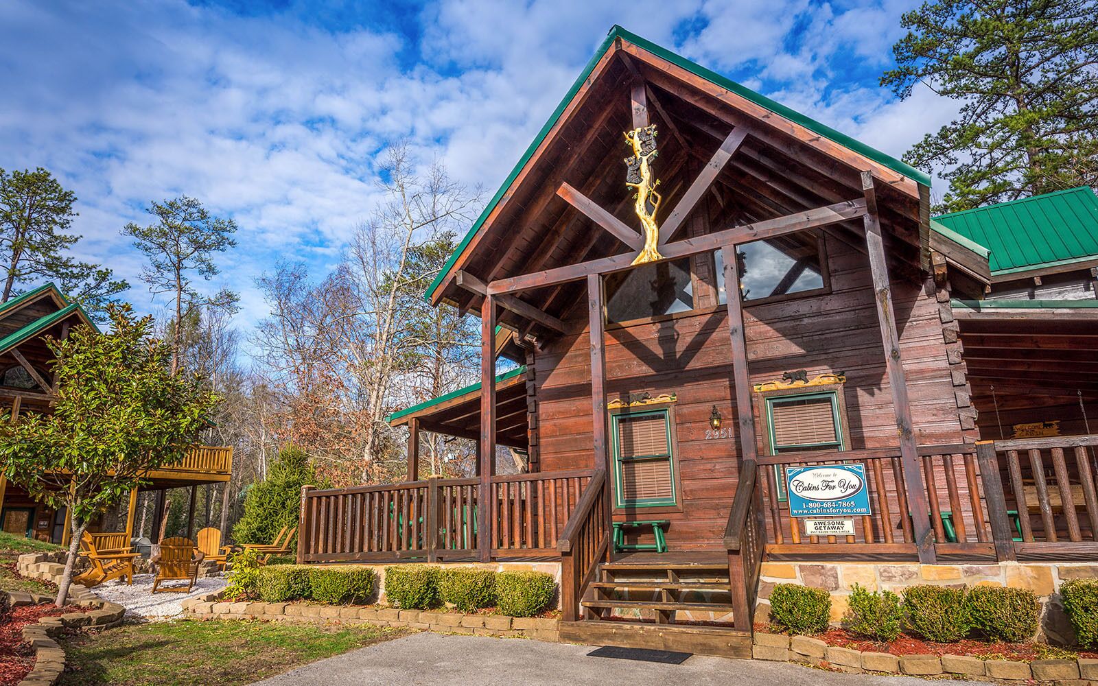 A wooden cabin with a green roof, a porch with a wooden railing, and a sign indicating it is a bed and breakfast.
