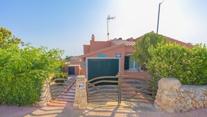 A villa named "Villa Marias" with a gated entrance, stone walls, and a clear sky.