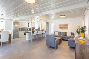 A modern open-plan living area with a kitchen, grey sofas, and a dining table. - Villa Constadina Large Private Pool, A/C, WiFi (Paxi)