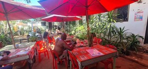 An outdoor dining area with red umbrellas, tables, and chairs. - Relax And Resort Angkor Guesthouse (Siem Reap)
