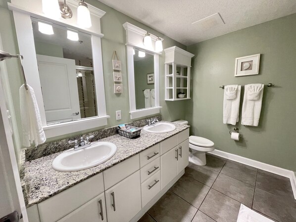 A bathroom with two sinks, a toilet, and a large mirror.