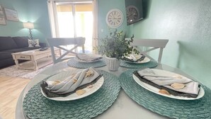 A dining table with four plates of food, a potted plant, and two wall clocks.