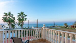 A balcony with a view of the sea, palm trees, and a chair. - Villa Jan Lui - Four Bedroom Villa, Sleeps 8 (Argaka)