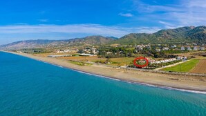 An aerial view of a coastal area with a beach, houses, and hills in the background. - Villa Jan Lui - Four Bedroom Villa, Sleeps 8 (Argaka)