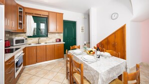 A compact kitchen with wooden cabinets, a microwave, and a dining area with a table set for two.