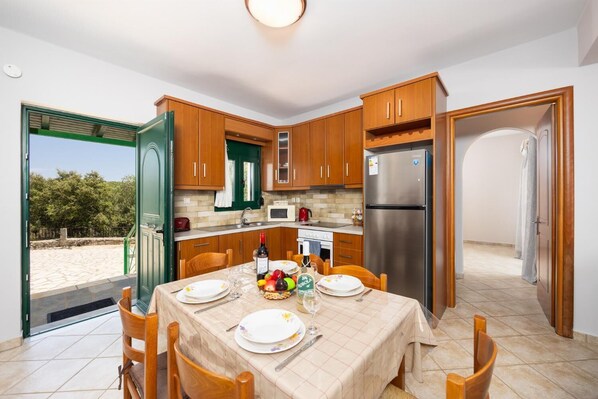 Una cocina moderna con armarios de madera, un refrigerador de acero inoxidable y una mesa de comedor lista para cuatro comensales.