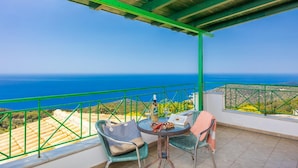 Een balkon met tafel en stoelen met uitzicht op de kust.