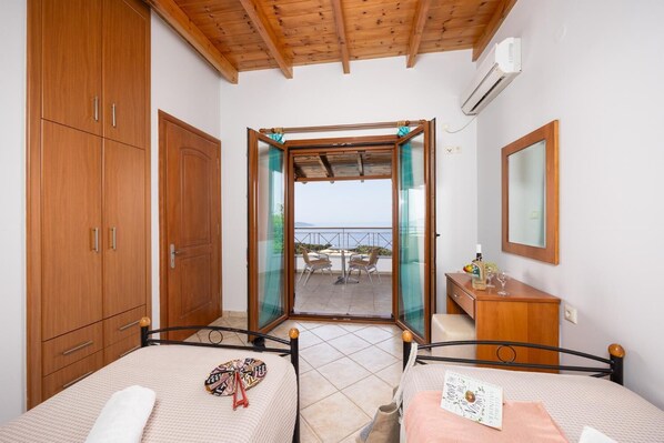 Une chambre avec deux lits, une armoire en bois et un balcon avec vue.