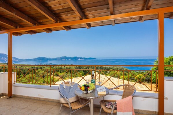 Eine Terrasse mit Tisch und Stühlen, die einen malerischen Ausblick auf eine Berglandschaft und ein Gewässer bietet.