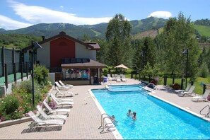 A swimming pool with lounge chairs and a building with a red facade.