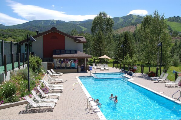 A swimming pool with lounge chairs and a building with a red facade. - RA513 | Newly Listed | Amazing Views | Winter Shuttle | Pool | Hot Tubs (Steamboat Springs)