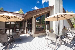 An outdoor patio with tables and chairs, large windows, and umbrellas. - RA513 | Newly Listed | Amazing Views | Winter Shuttle | Pool | Hot Tubs (Steamboat Springs)