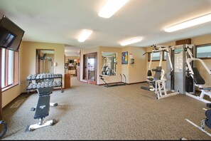 A gym with various exercise equipment, including dumbbells, a bench, and cardio machines.