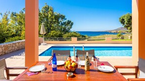 Une table dressée pour deux personnes, avec vue sur la mer et une piscine.