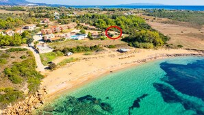 Vue aérienne d’une station balnéaire avec des villas, une plage et des eaux d’un bleu limpide.